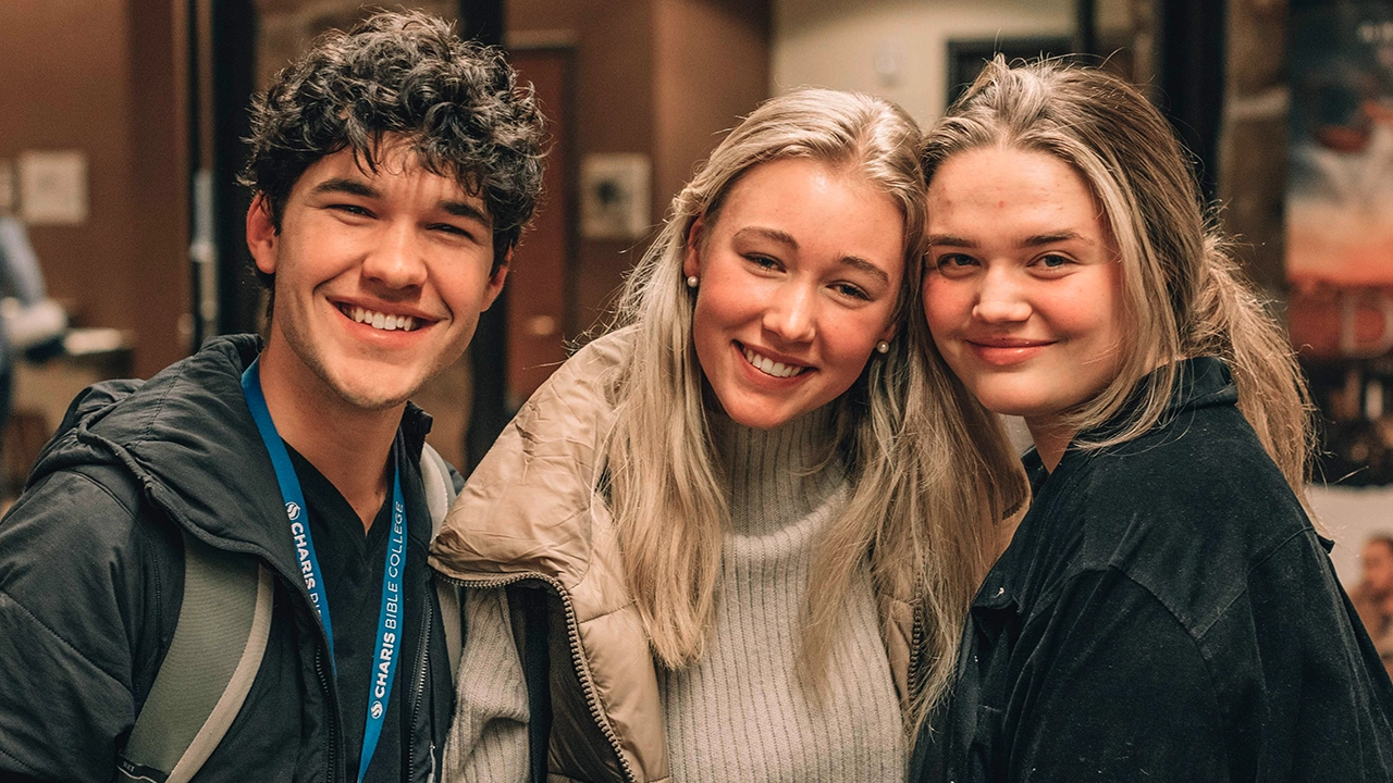 Three students smiling and enjoying their time at Charis Bible College, captured in a warm and welcoming setting.